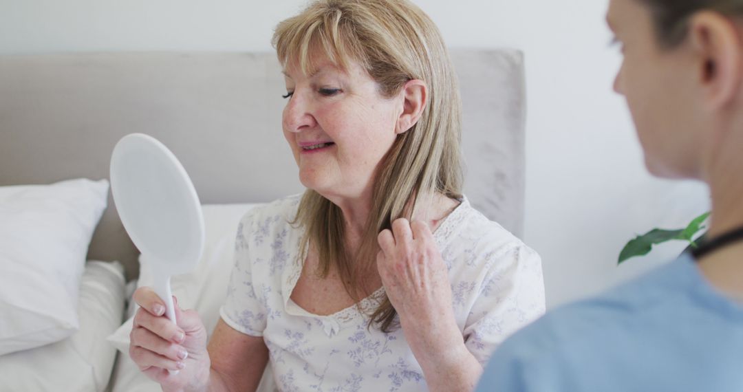 Senior Woman Smiling in Mirror with Caregiver Assistance - Free Images, Stock Photos and Pictures on Pikwizard.com