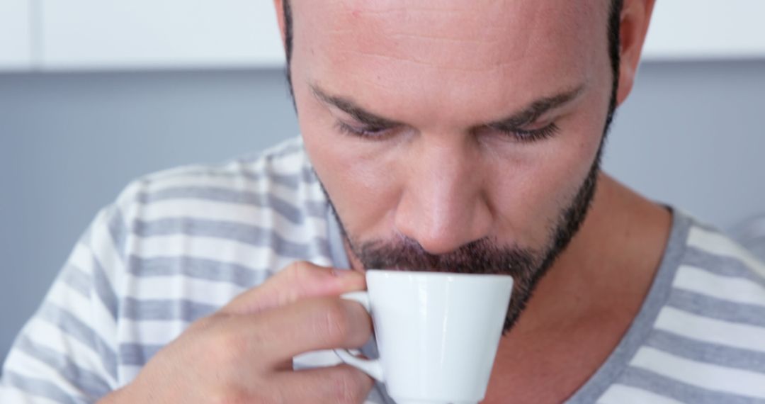 Man Drinking Coffee in Striped Shirt with Intense Focus - Free Images, Stock Photos and Pictures on Pikwizard.com