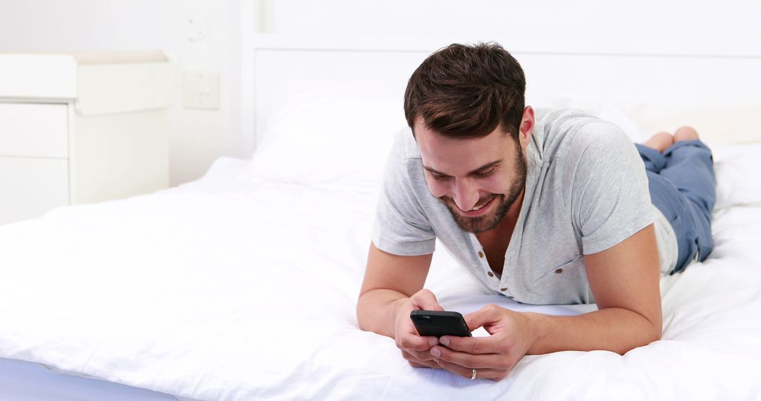 Man Lying on Bed Using Smartphone and Smiling - Free Images, Stock Photos and Pictures on Pikwizard.com