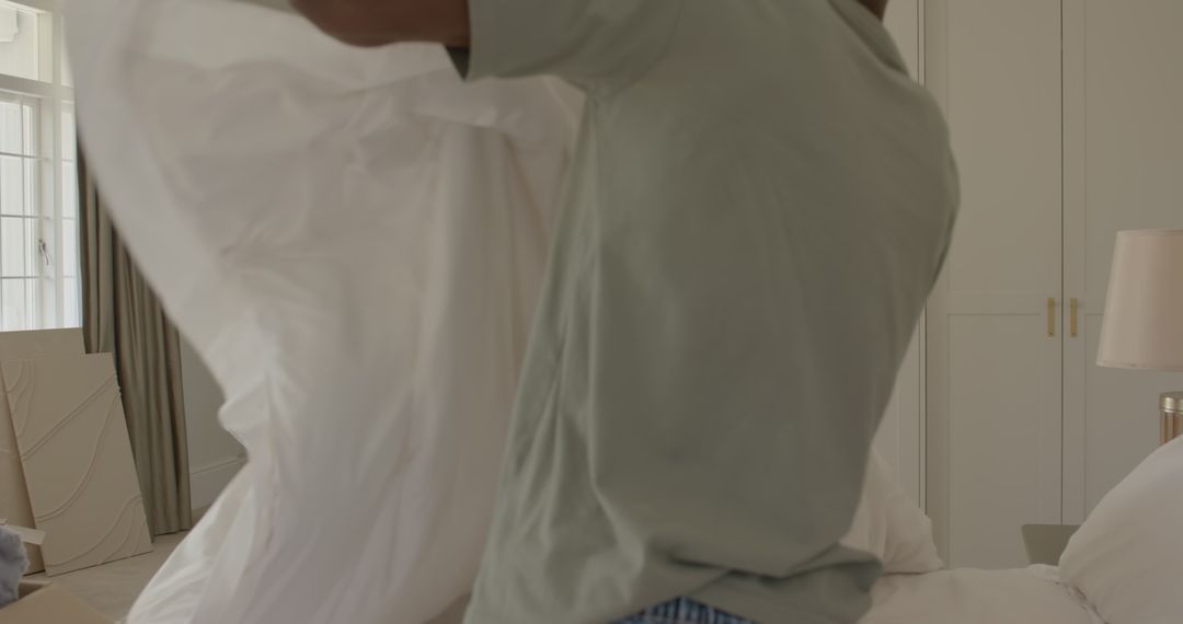 Man Unpacking White Fabric at Home in Bedroom Setting