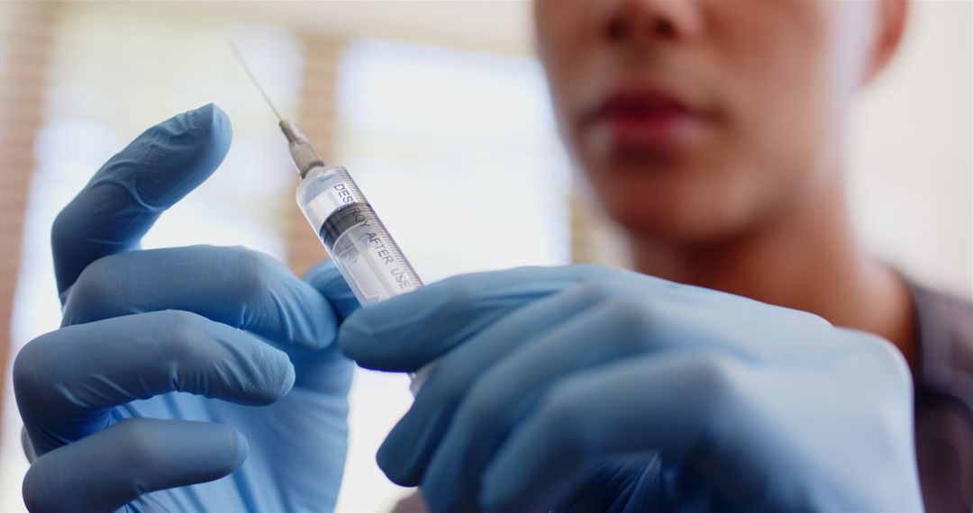 Gloved Hands Preparing Syringe for Injection