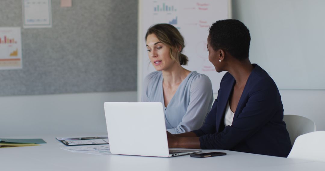 Two Businesswomen Discussing Work in Office with Laptop - Free Images, Stock Photos and Pictures on Pikwizard.com