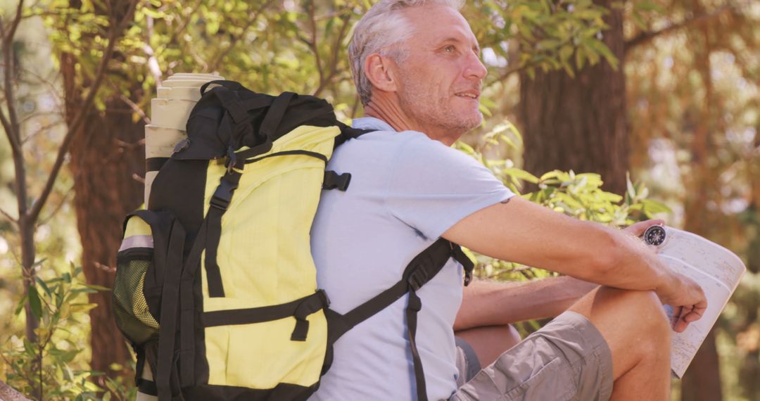Pensive Older Hiker with Map Resting in Forest