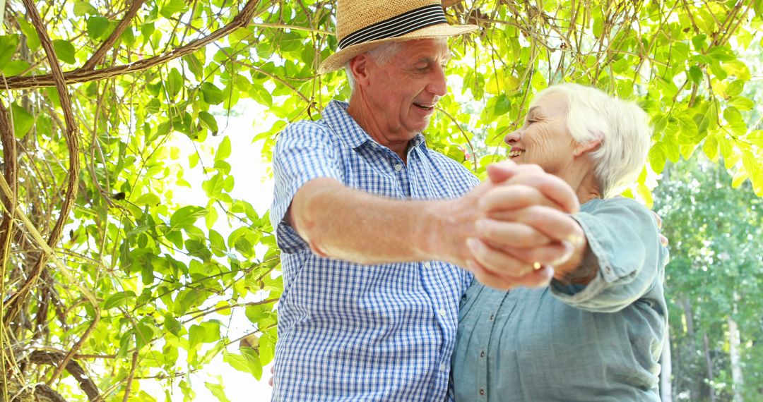 Happy Senior Couple Dancing Outdoors Under Greenery - Free Images, Stock Photos and Pictures on Pikwizard.com