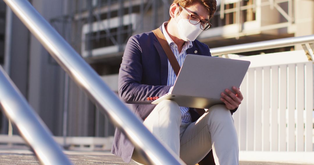 Businessman Wearing Mask Using Laptop Outdoors in Urban Area - Free Images, Stock Photos and Pictures on Pikwizard.com