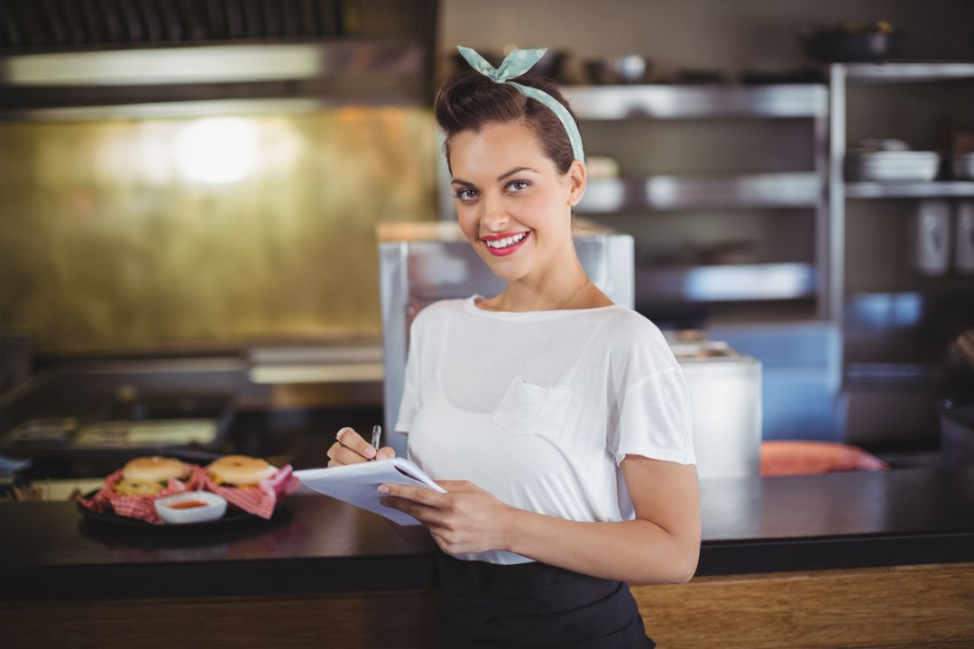 Smiling Waitress in Busy Restaurant Kitchen Taking Orders