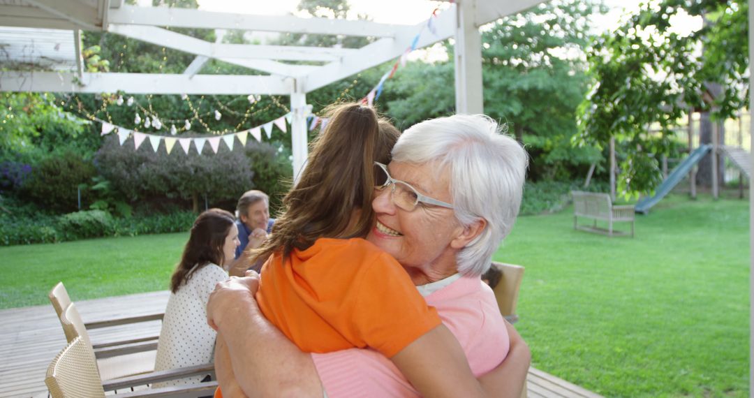 Smiling Grandmother Hugging Granddaughter Outdoors at Family Gathering - Free Images, Stock Photos and Pictures on Pikwizard.com