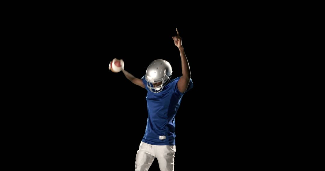 Celebrating American Football Player Holding Football on Black Background - Free Images, Stock Photos and Pictures on Pikwizard.com