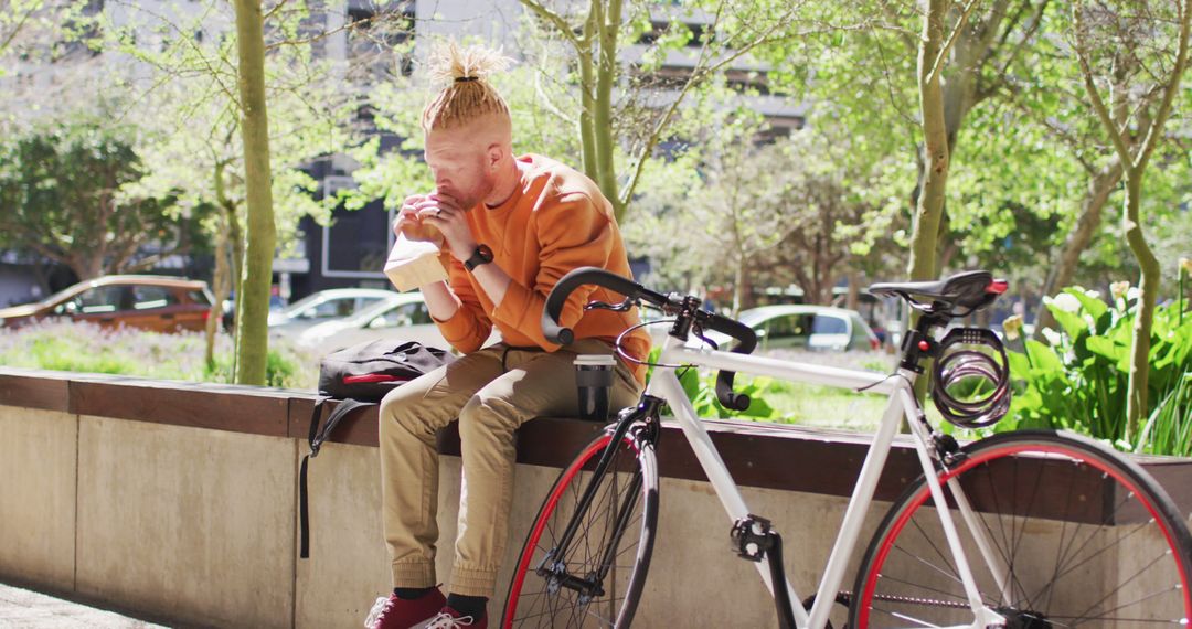 Young Man Enjoying Snack Outdoors Near Bicycle - Free Images, Stock Photos and Pictures on Pikwizard.com