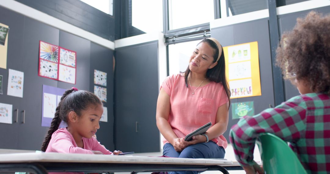 Teacher Assisting Students in a Bright Classroom