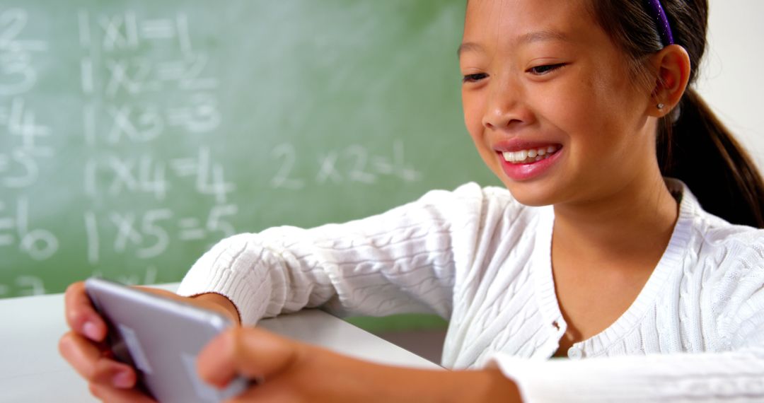 Cheerful Schoolgirl Engaging with Educational App in Classroom
