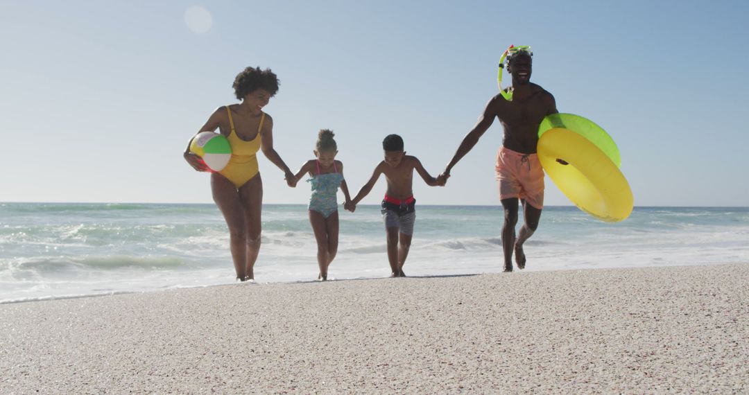 Smiling african american family with inflatables running on sunny beach - Free Images, Stock Photos and Pictures on Pikwizard.com