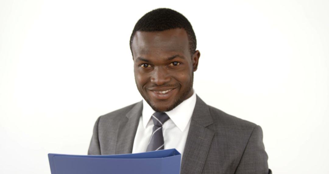 Confident Businessman Holding Blue Folder Smiling at Camera - Free Images, Stock Photos and Pictures on Pikwizard.com