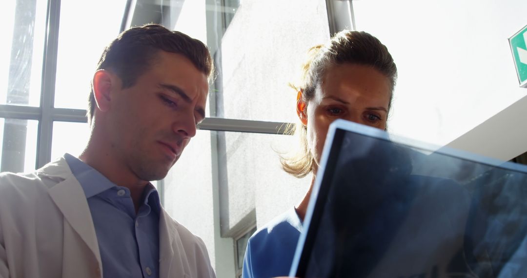 Doctors Collaborating on Digital Device in Modern Hospital - Free Images, Stock Photos and Pictures on Pikwizard.com