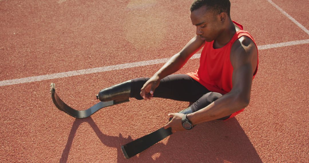 Paralympic sprinter adjusting prosthetic leg before race on track - Free Images, Stock Photos and Pictures on Pikwizard.com