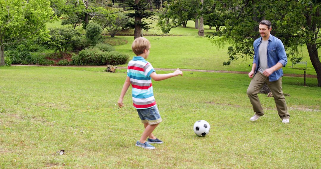 Father and son playing soccer in park on a sunny day - Free Images, Stock Photos and Pictures on Pikwizard.com