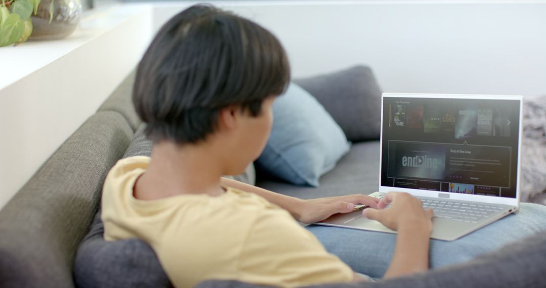 Young Asian Man Streaming Video on Laptop with Modern Interface