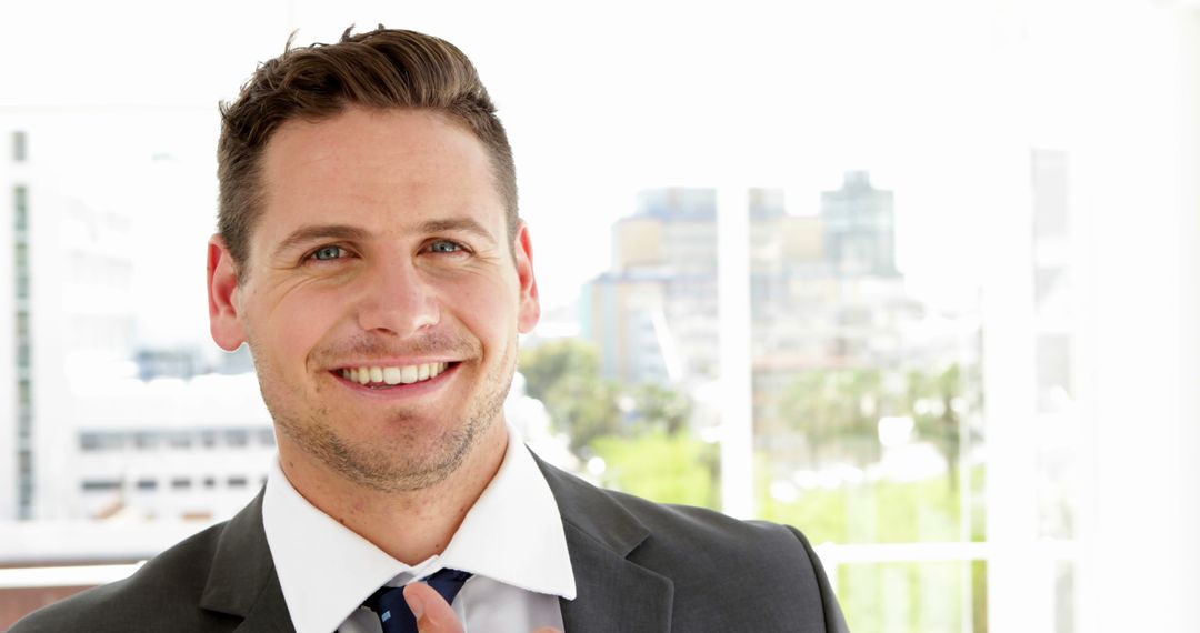 Smiling Businessman Adjusting Tie in Bright Modern Office - Free Images, Stock Photos and Pictures on Pikwizard.com