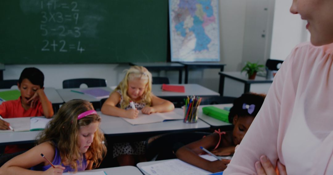 Diverse Children Focused in Classroom Setting with Mentor Overseeing