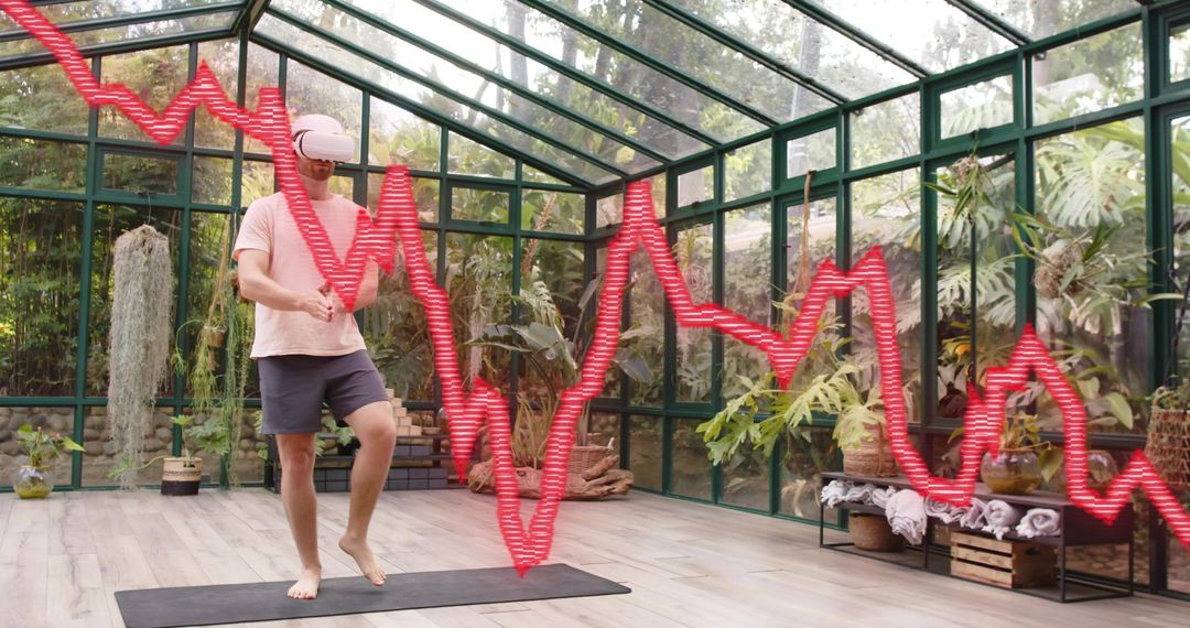 Man Wearing VR Headset Practicing Balance on Yoga Mat in Glass Greenhouse with Red Waveform