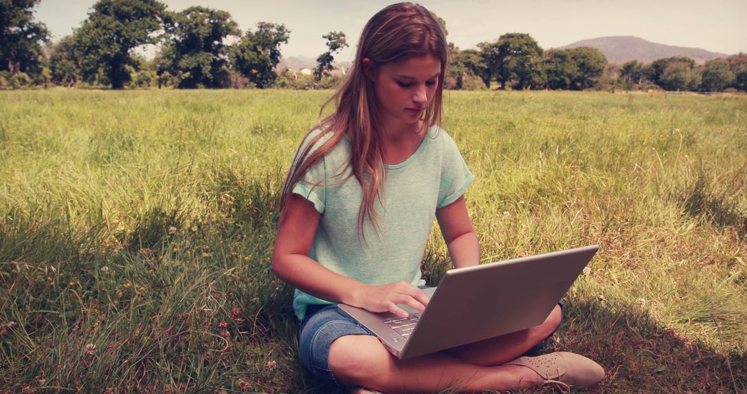 Young Woman Working Outdoors on Laptop in Sunny Field - Free Images, Stock Photos and Pictures on Pikwizard.com