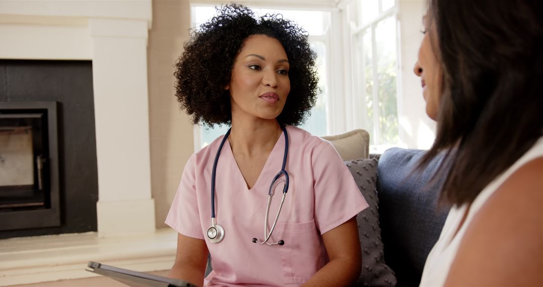 Nurse in Pink Scrubs Consulting with Patient Using Tablet at Home
