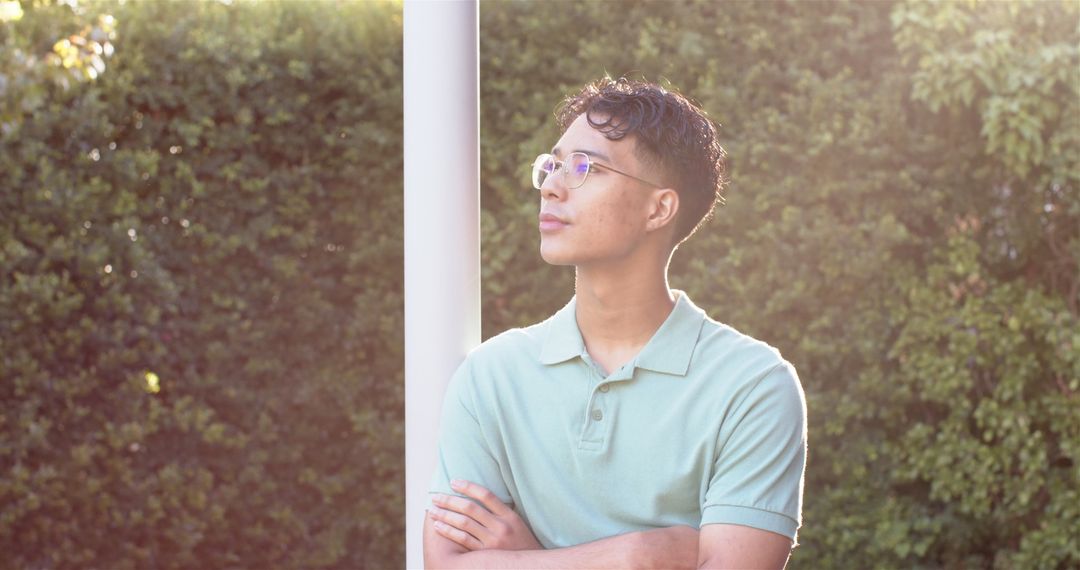 Thoughtful Young Man with Glasses in Sunlit Garden