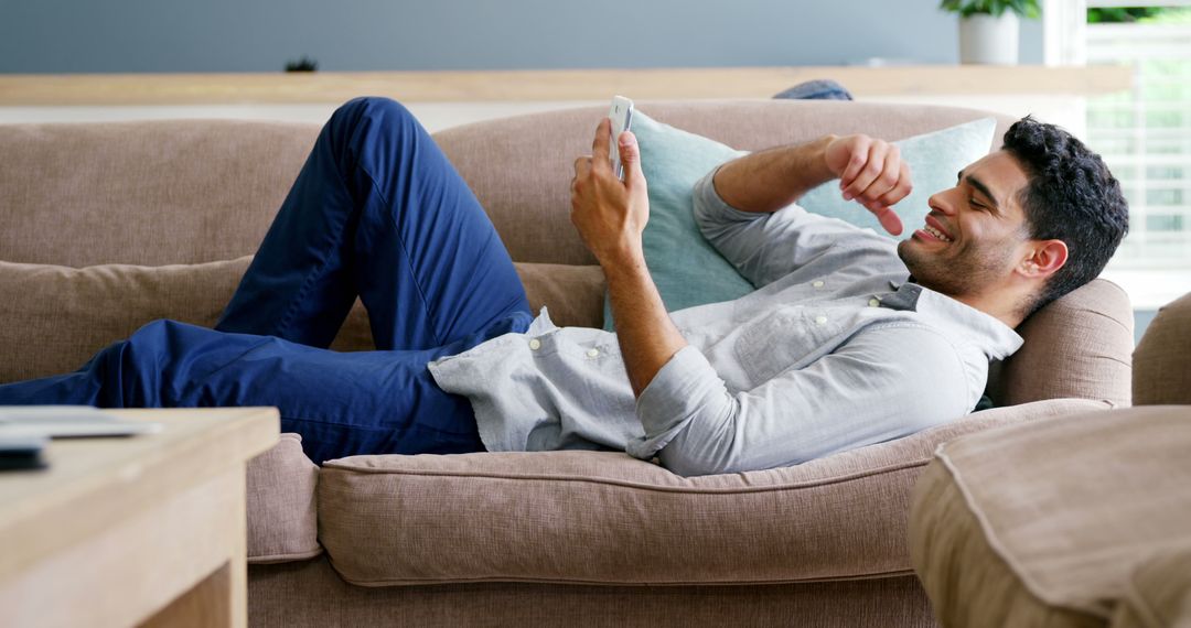 Man Relaxing on Couch Using Smartphone Indoors - Free Images, Stock Photos and Pictures on Pikwizard.com