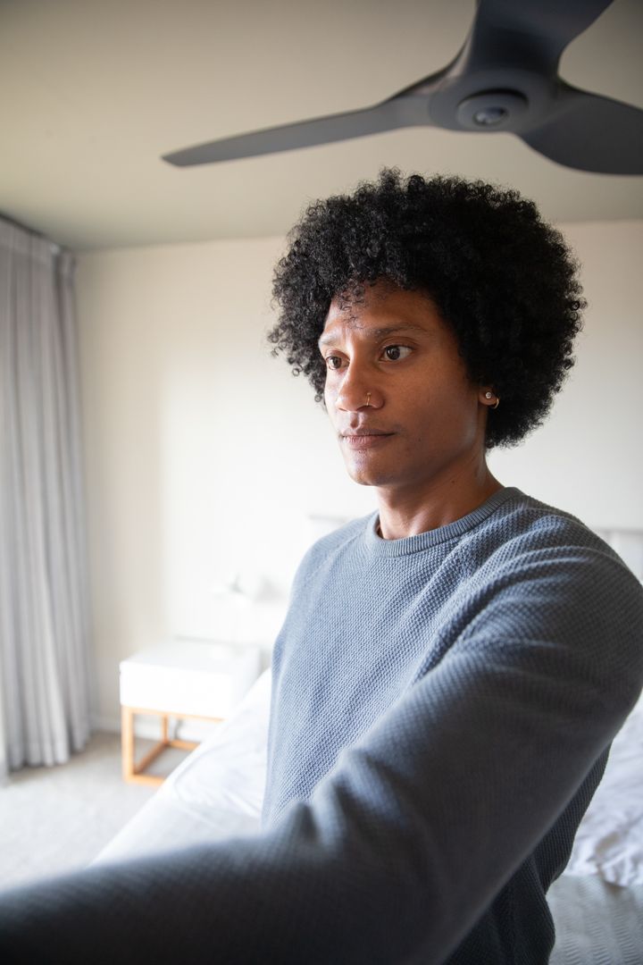 Man Relaxing in Minimalist Bedroom Setting Near Bed
