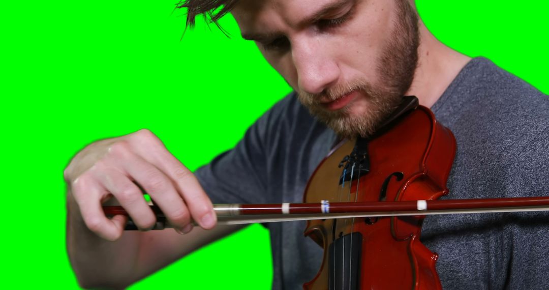 Man Playing Violin with Focused Expression on Green Background - Free Images, Stock Photos and Pictures on Pikwizard.com