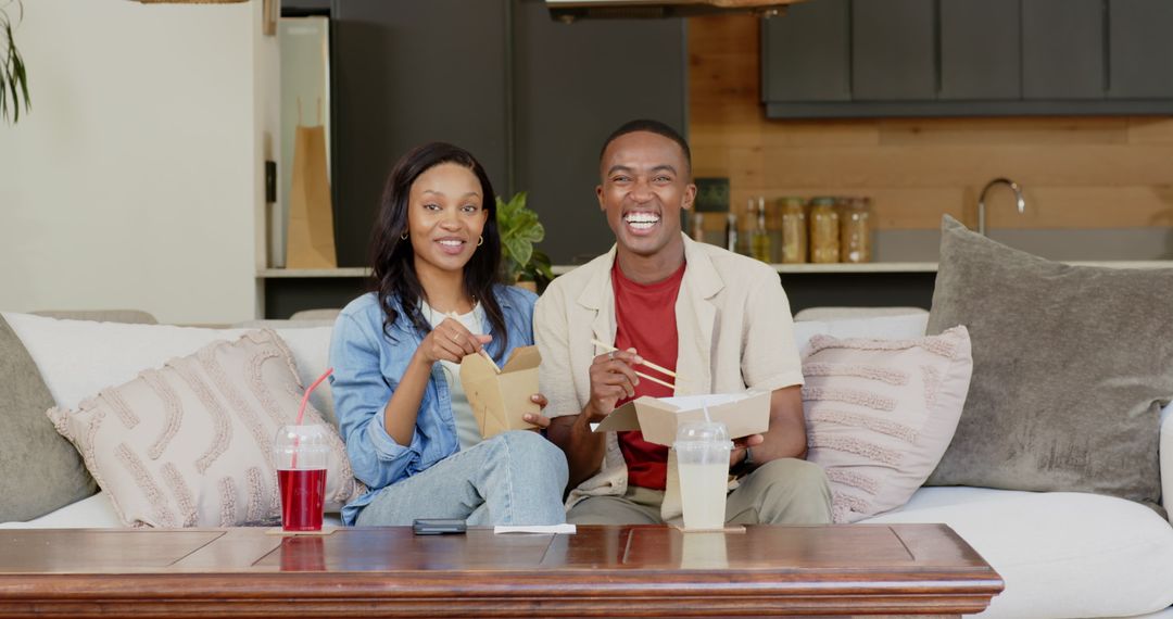 Couple Enjoying Takeout on Sofa with Drinks in Stylish Living Room