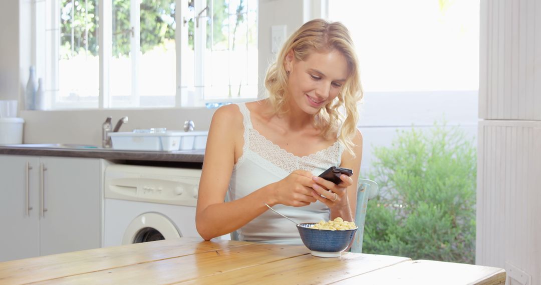 Smiling Woman Using Smartphone While Eating Breakfast at Home - Free Images, Stock Photos and Pictures on Pikwizard.com