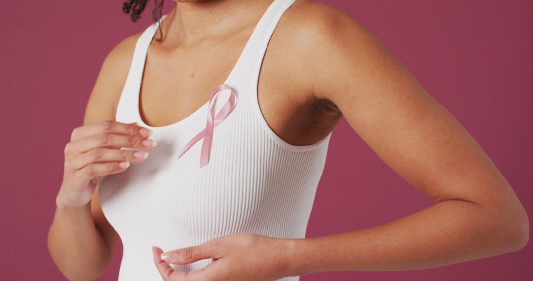 Image of biracial woman touching her pink breast cancer ribbon - Free Images, Stock Photos and Pictures on Pikwizard.com