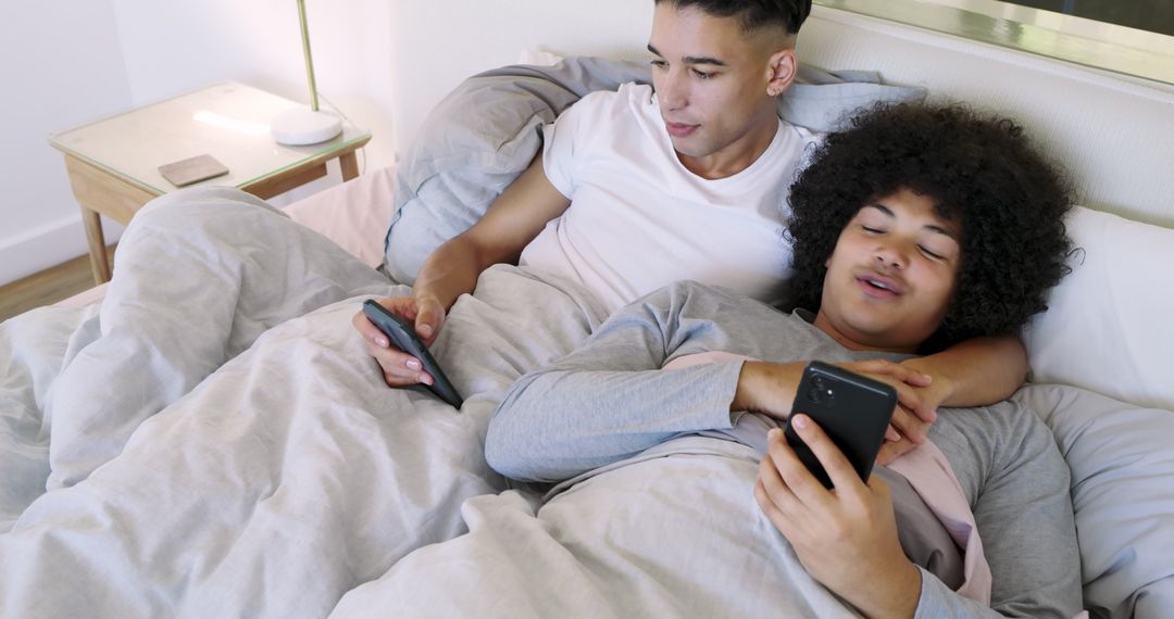 Father and Son Relaxing in Bed with Gadgets for Family Bonding