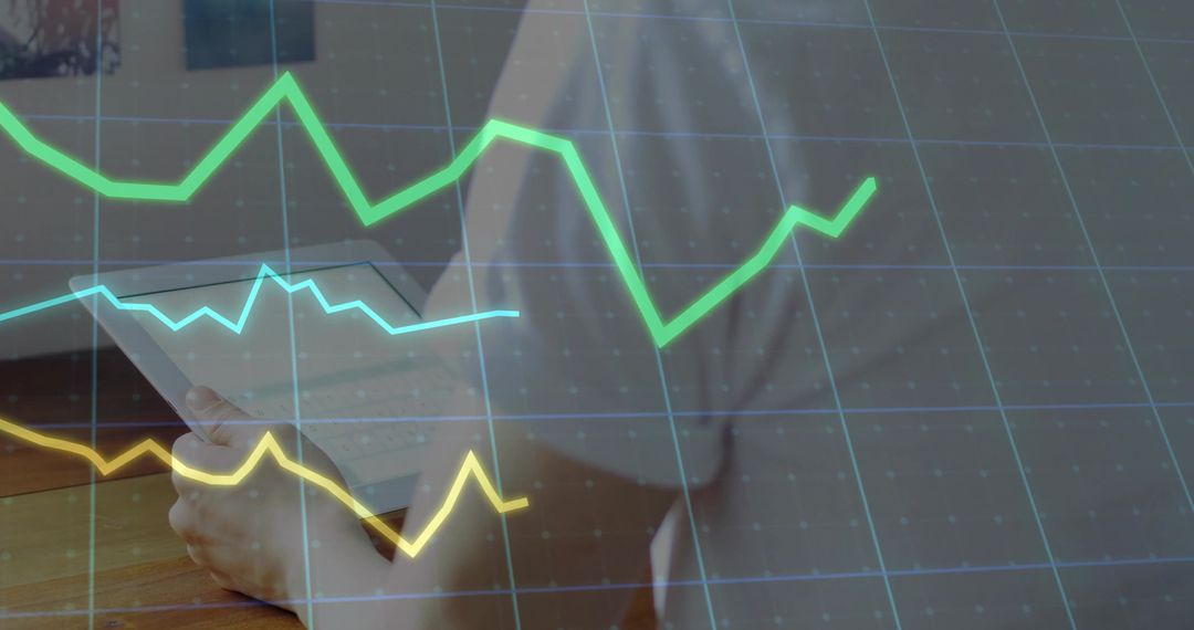 Business Professional Analyzing Data on Desktop with Line Graph Overlay