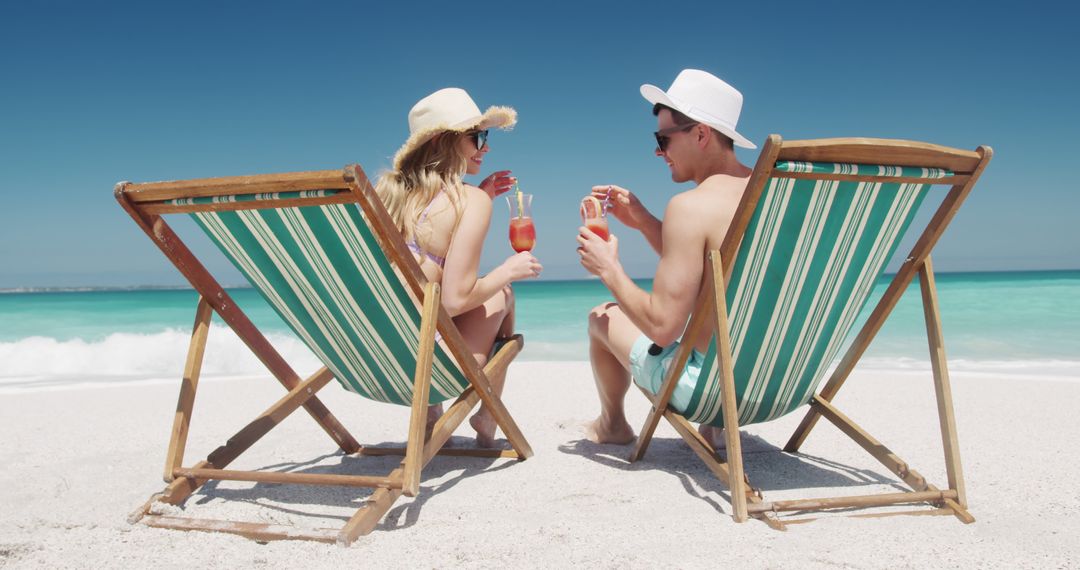 Couple Relaxing on Beach with Cocktails in Deck Chairs under Clear Sky - Free Images, Stock Photos and Pictures on Pikwizard.com