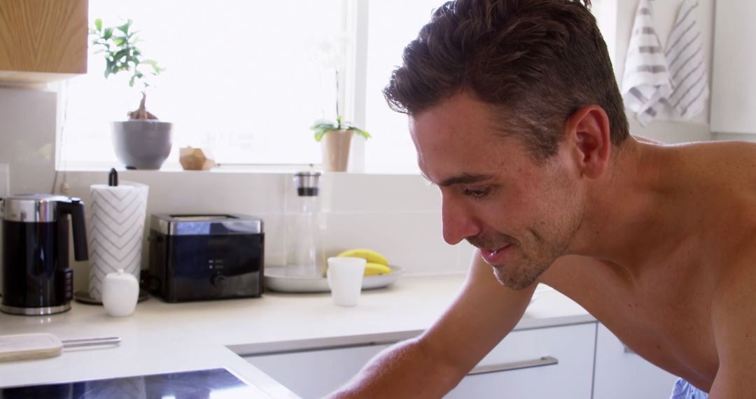 Man Smiling While Cooking in Modern Bright Kitchen - Free Images, Stock Photos and Pictures on Pikwizard.com