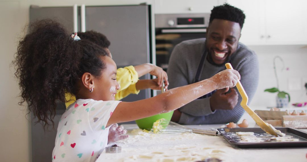 Father Laughing While Daughter Placing Cookie Dough on Tray in Bright Home Kitchen
