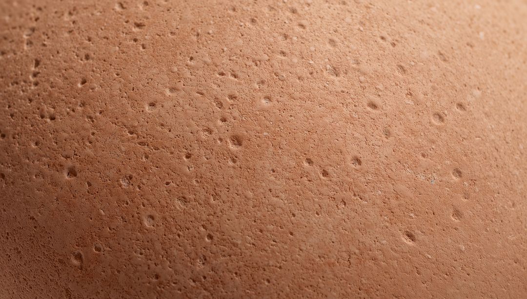 Macro brown eggshell revealing porous matte texture with pitted speckled detail