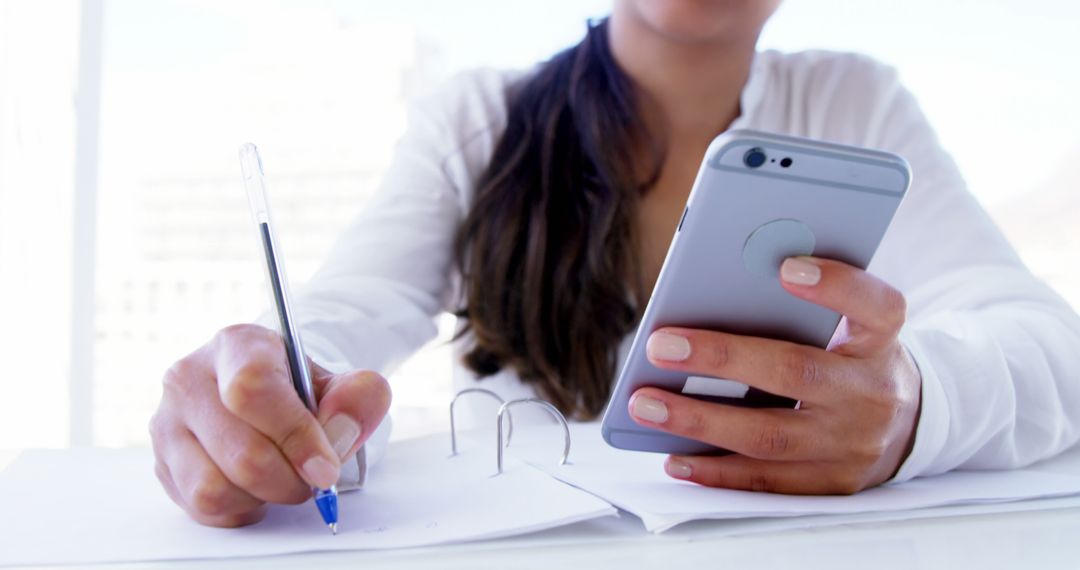 Woman Working on Paperwork While Using Smartphone at Desk - Free Images, Stock Photos and Pictures on Pikwizard.com