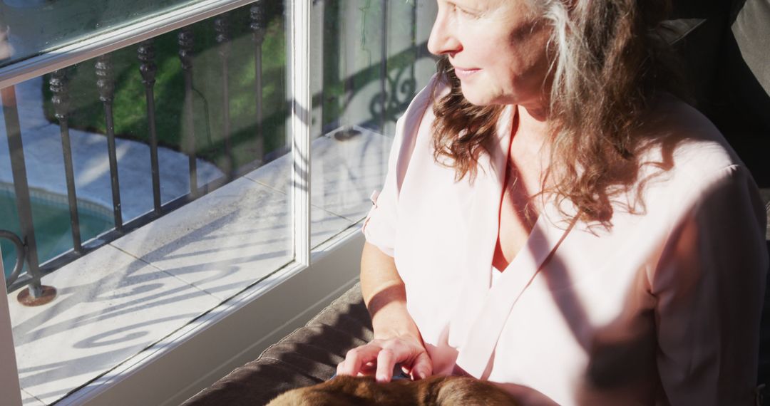 Senior Woman Relaxing By Window With Cat In Sunlight - Free Images, Stock Photos and Pictures on Pikwizard.com