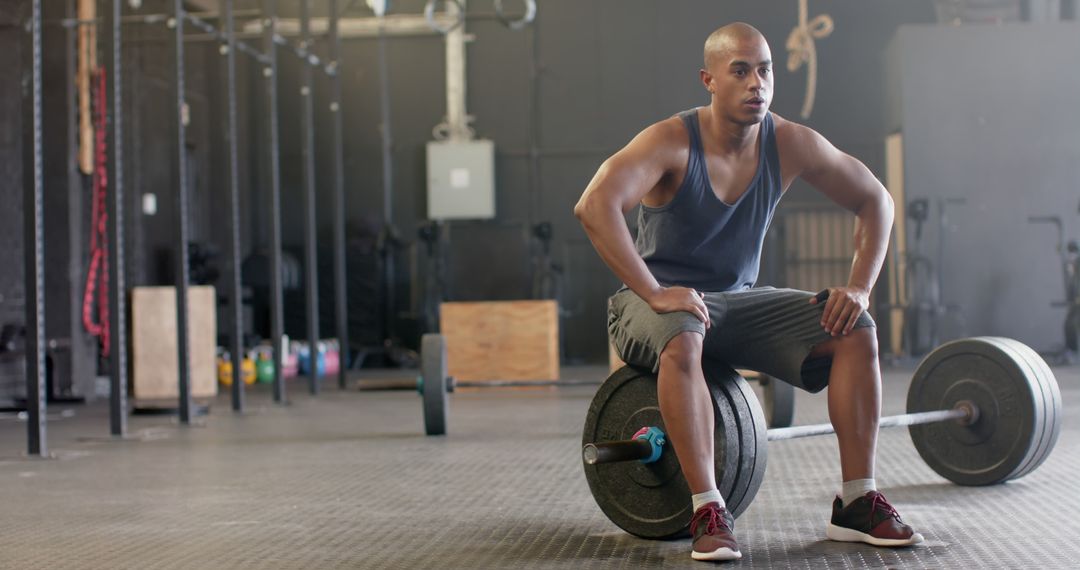 Exhausted biracial sportsman resting on weight bar and sweating at gym - Free Images, Stock Photos and Pictures on Pikwizard.com