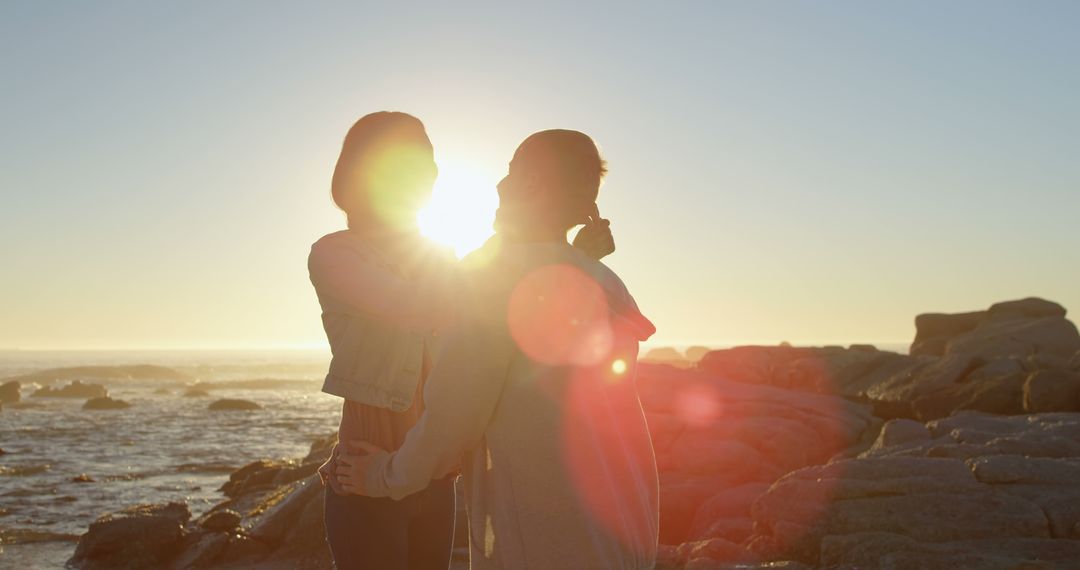 Romantic Couple Embracing at Sunset on Rocky Shoreline - Free Images, Stock Photos and Pictures on Pikwizard.com