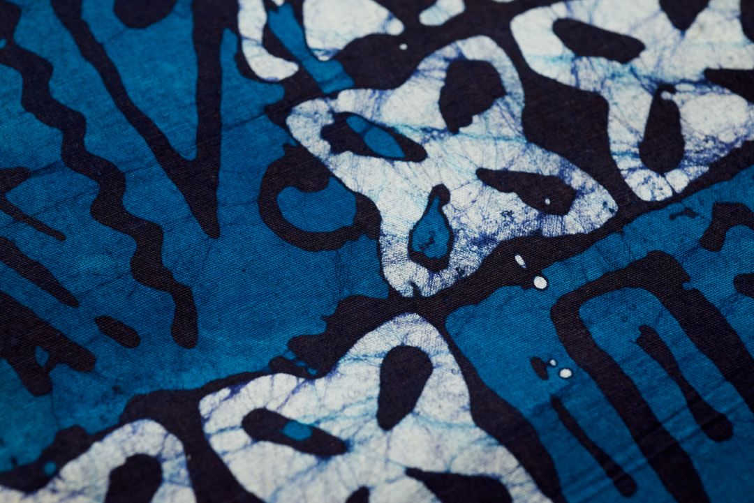 Close-up showing indigo batik textile with cracked resist lines and abstract motifs