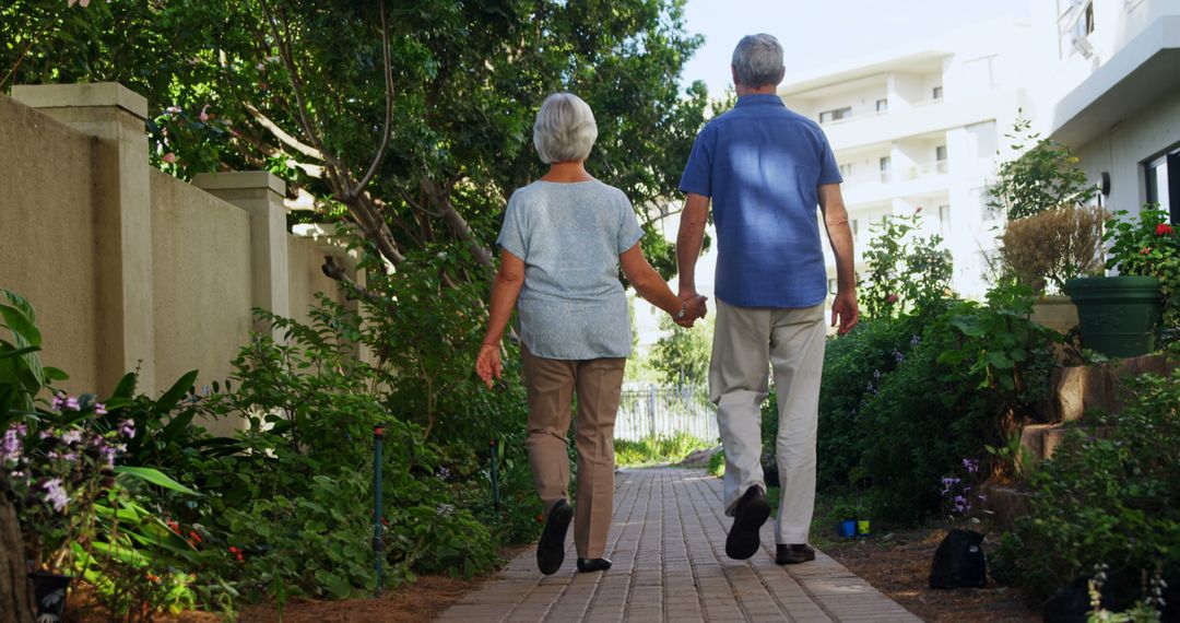 Senior Couple Walking Hand in Hand in Garden Pathway - Free Images, Stock Photos and Pictures on Pikwizard.com