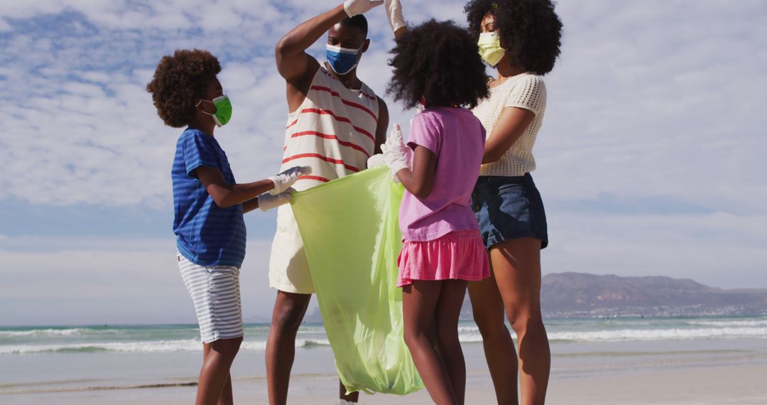 African american parents with two children wearing face masks collecting rubbish from the beach - Free Images, Stock Photos and Pictures on Pikwizard.com