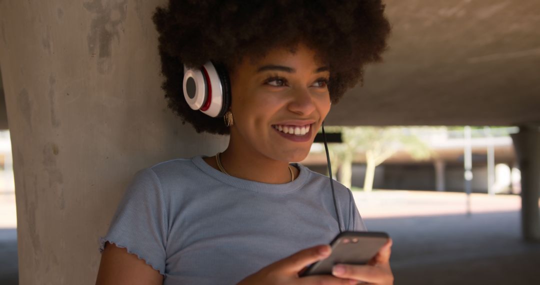 Smiling Woman with Headphones Enjoying Music on Smartphone - Free Images, Stock Photos and Pictures on Pikwizard.com