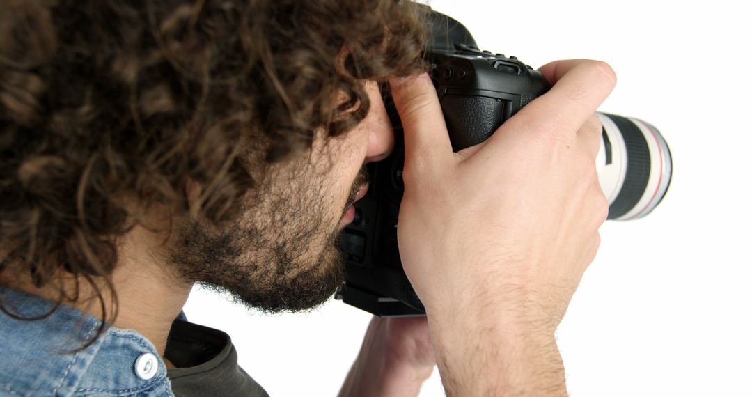 Photographer with curly hair using DSLR camera on white background - Free Images, Stock Photos and Pictures on Pikwizard.com