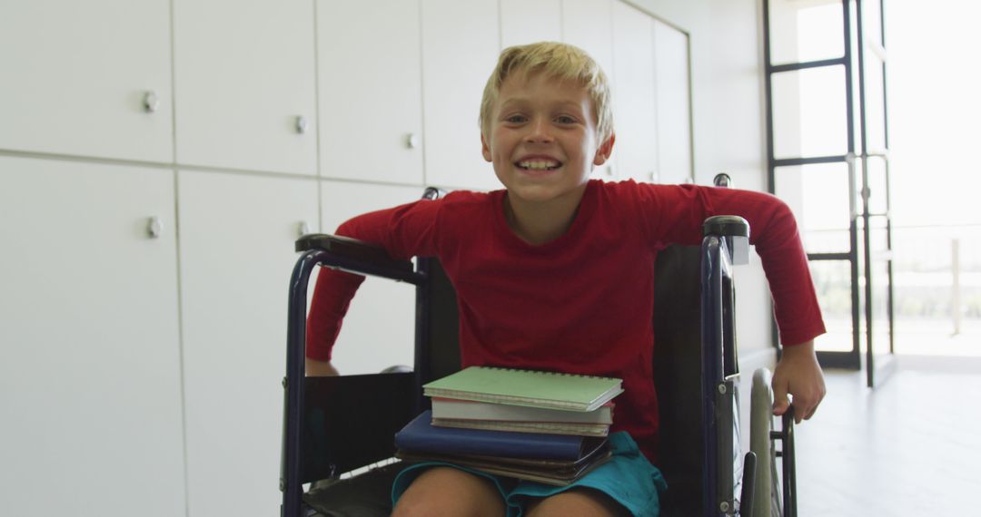 Joyful Disabled Boy in Wheelchair with Books in School Hallway