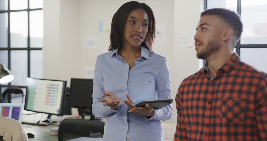 Diverse Colleagues Engaged in Office Discussion with Tablet